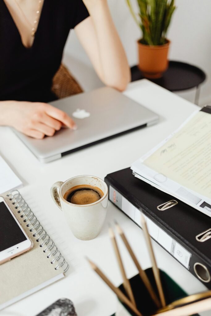 A cozy office desk setup featuring a laptop, coffee, and documents for a productive workday.
