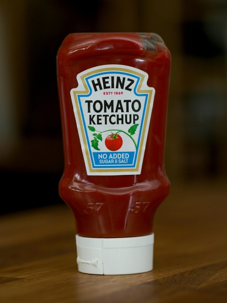 A vertical close-up of a Heinz tomato ketchup bottle with no added sugar or salt.